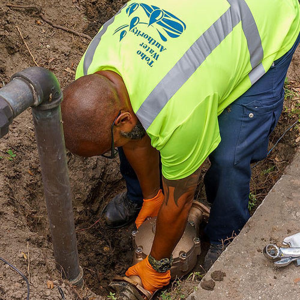 Image of field technician installing water meter. 