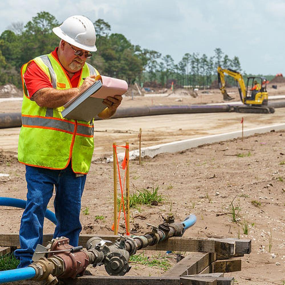 Image of construction inspector looking at hydrant meter. 