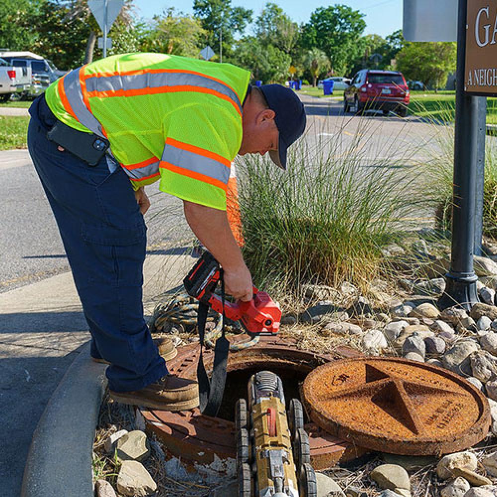 Image of utility worker using machinery near manhole