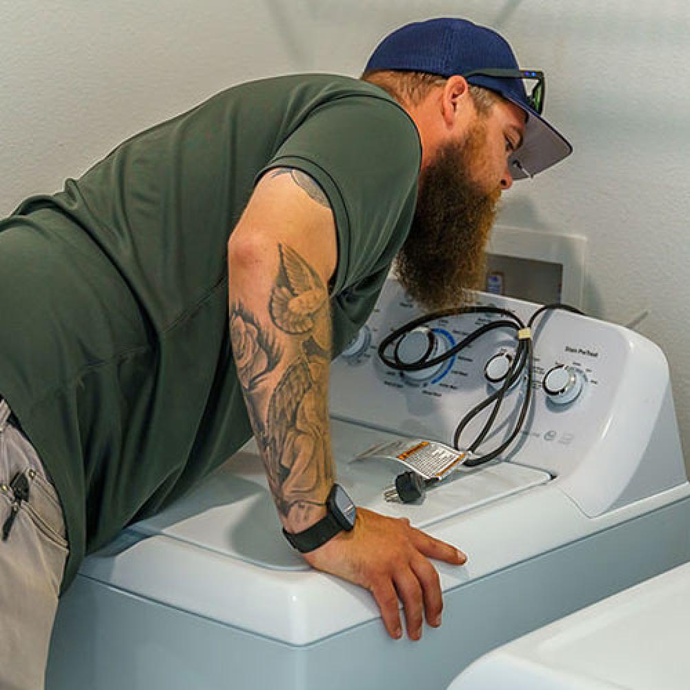 Image of inspector looking at washing machine connections. 