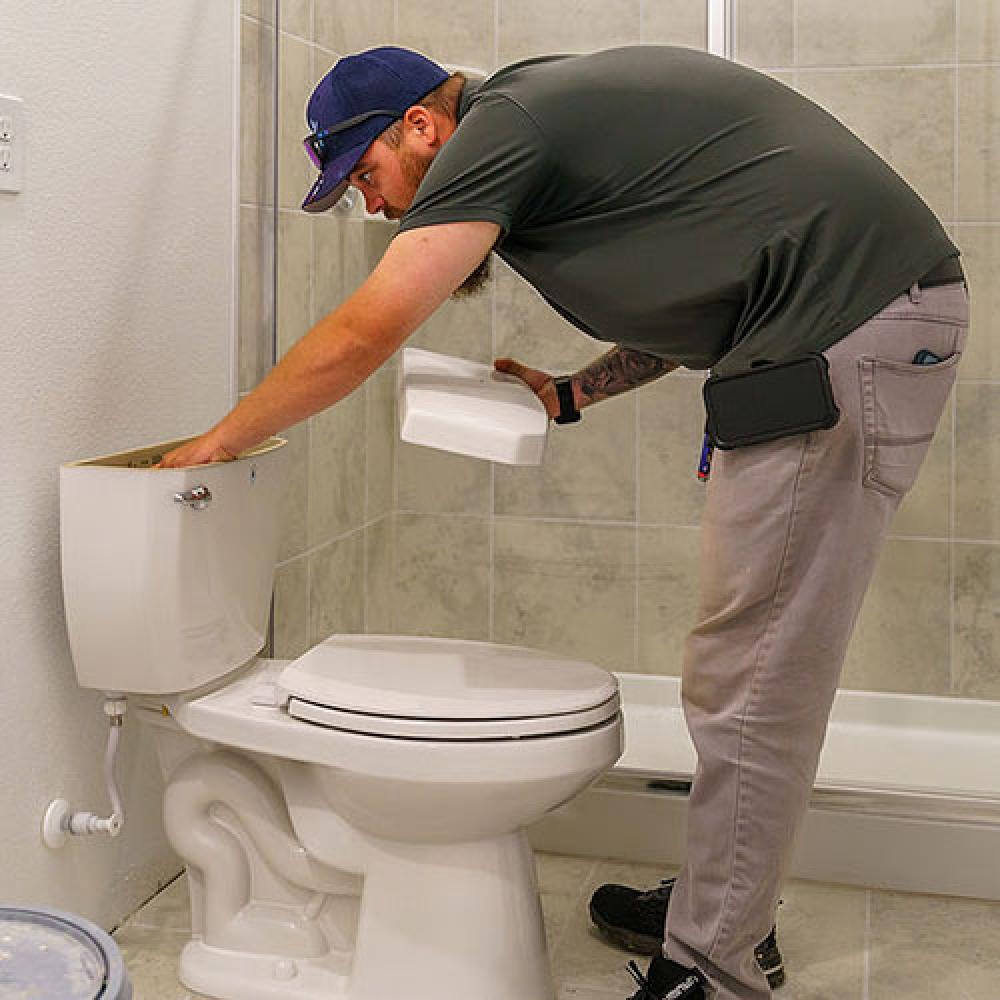 Image of construction inspector checking toilet installation. 