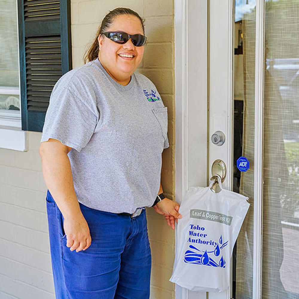 Image of water quality specialist lady leaving a test kit at a residence.