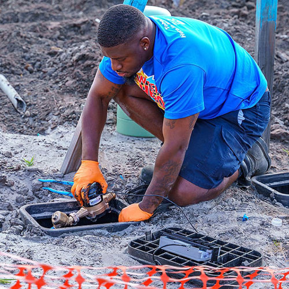 Image of field technician installing water meter at construction site.