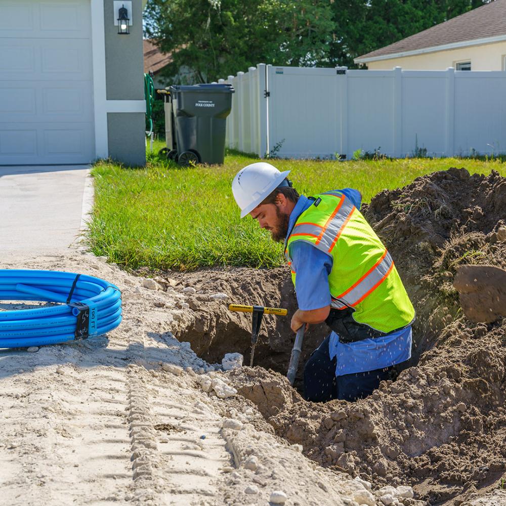 Image of construction worker digging a hole. 