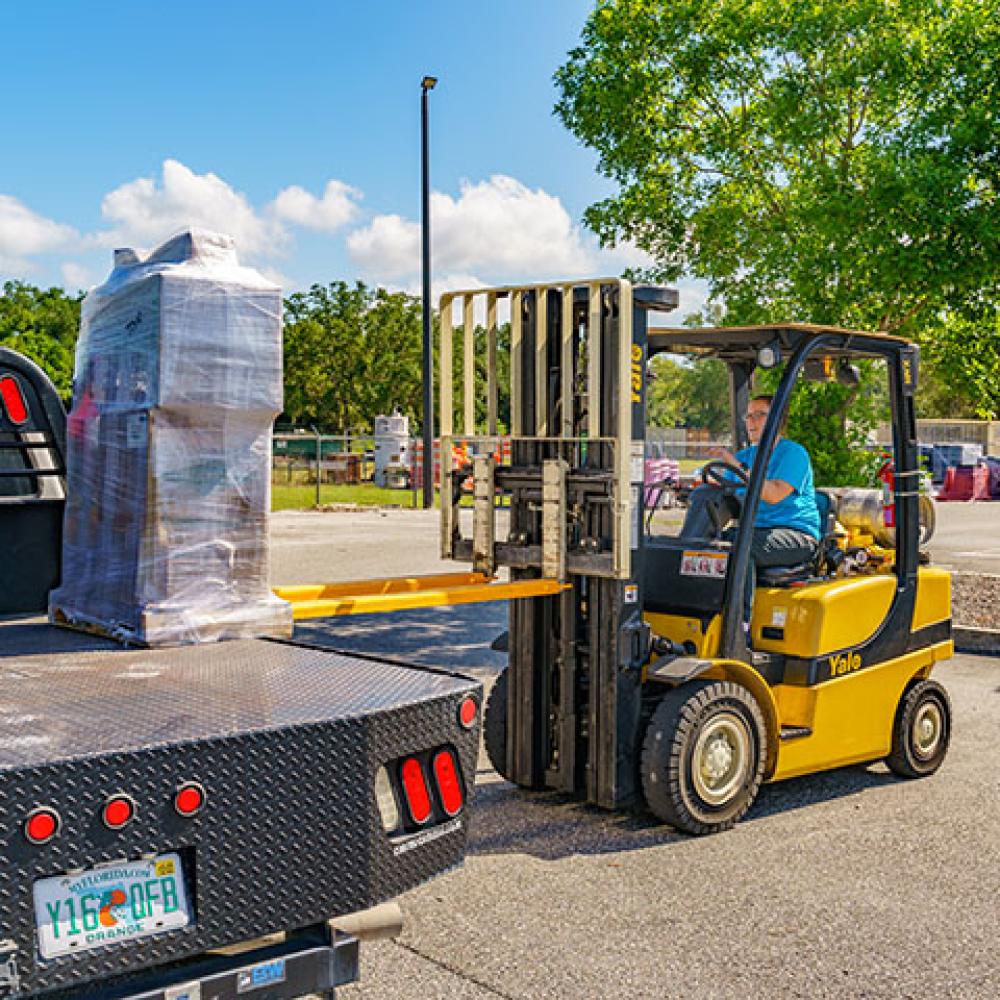 Image of employee removing cargo from a truck with a forklift.