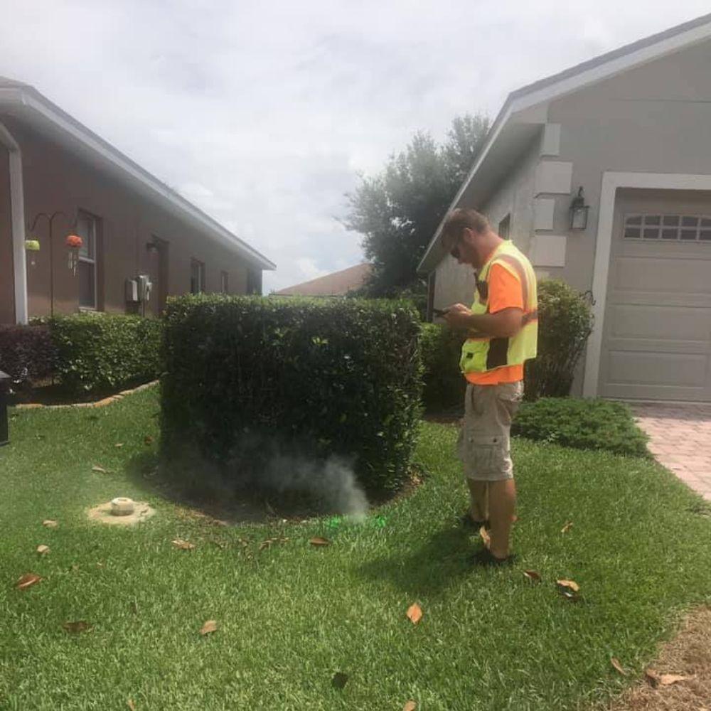 Image of technician during a smoke test seeing smoke coming from a sewer line on a property.