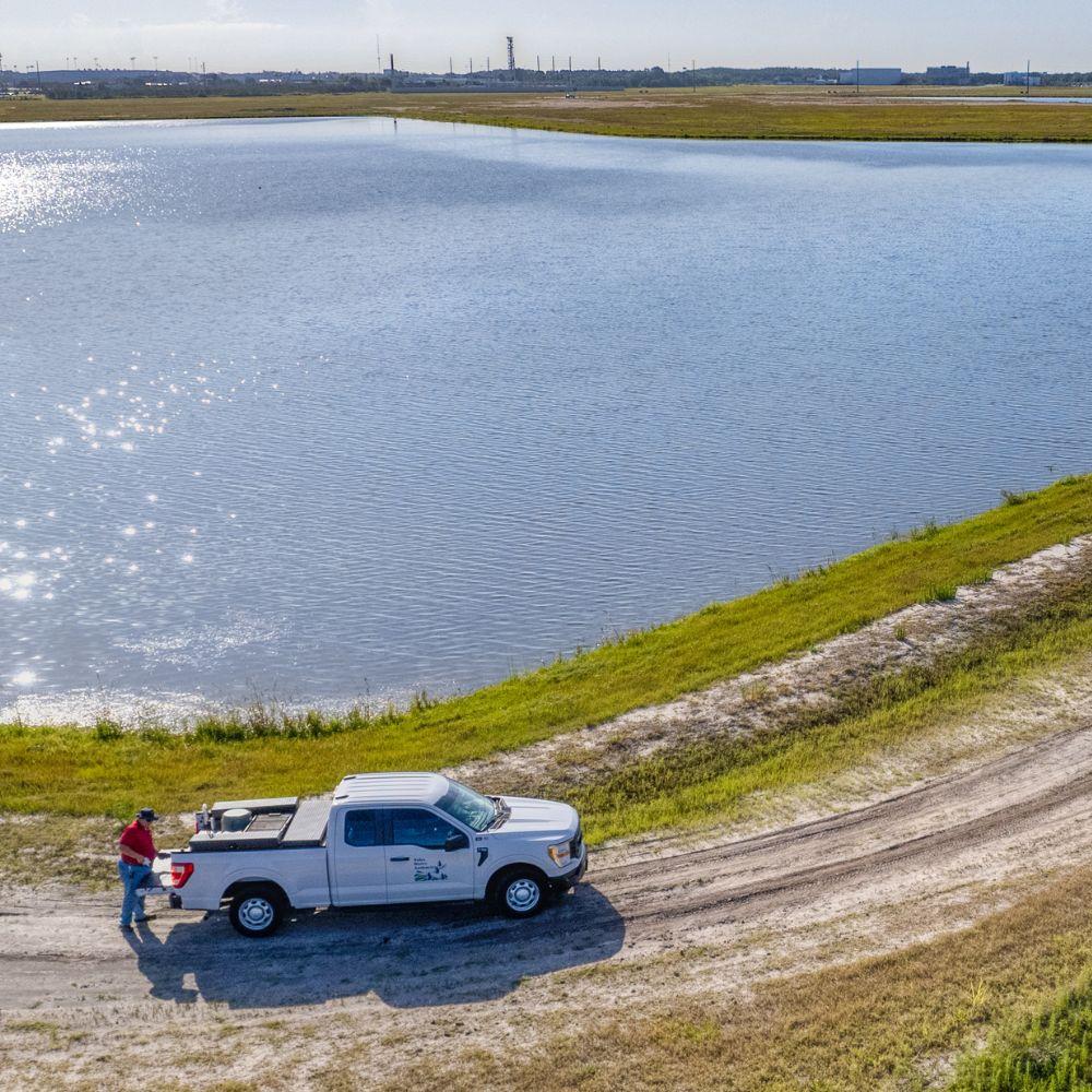 Image of technician at Toho Reservoir standing behind vehicle. 