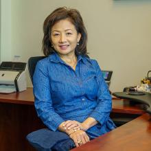 Image of lady in office setting sitting at her desk. 